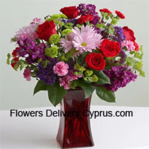 Roses rouges, œillets roses et autres fleurs saisonnières assorties dans un vase en verre