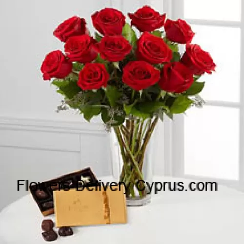 12 Roses rouges avec des fougères dans un vase et une boîte de chocolats Godiva (Nous nous réservons le droit de substituer les chocolats Godiva par des chocolats de valeur équivalente en cas de non disponibilité des mêmes. Stock limité)